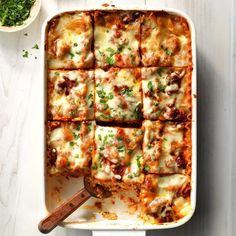 a casserole dish with meat and cheese on it, next to a bowl of parsley