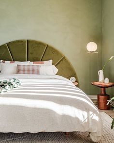 a bedroom with green walls and white bedding