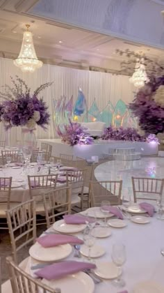 tables and chairs are set up for a formal function with purple flowers in vases