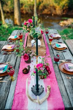 the table is set with plates and flowers on it, along with other place settings