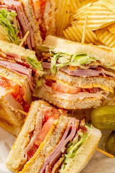 a sandwich cut in half sitting on top of a table next to some potato chips