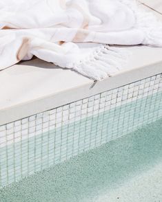 a towel sitting on top of a swimming pool next to a white tiled wall and floor