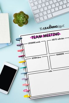 a team meeting planner on top of a desk next to a keyboard, phone and other office supplies