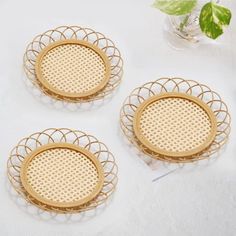 three round bamboo coasters on a white table with flowers and greenery in the background