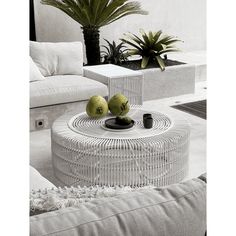 two green apples sitting on top of a table next to white couches and potted plants