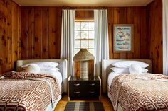 two beds in a room with wood paneling