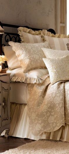 a bed with white sheets and pillows on top of it next to a night stand