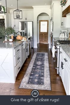 a kitchen with an area rug on the floor and white cabinets in front of it