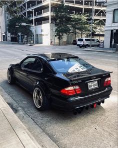 a black sports car parked on the side of the road in front of a building