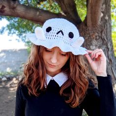 a woman wearing a white crocheted hat with a ghost on it