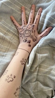 a person's hand with tattoos on it laying on top of a bed next to a blanket