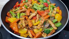 a wok filled with chicken, peppers and broccoli