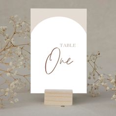 a white table sign sitting on top of a wooden block next to some baby's breath flowers