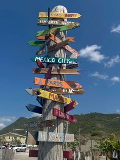 a wooden pole with many different signs on it's sides and the sky in the background