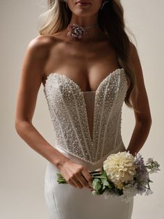 a beautiful woman in a white dress holding a flower bouquet and posing for the camera