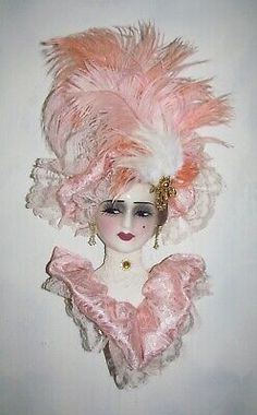 a doll with pink feathers on it's head and hair in the shape of a woman