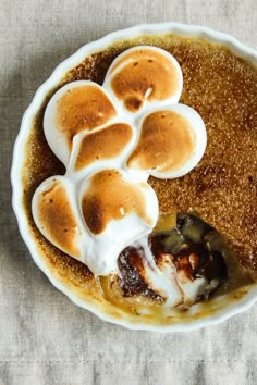 a pie with marshmallows and other toppings in a white bowl on a table