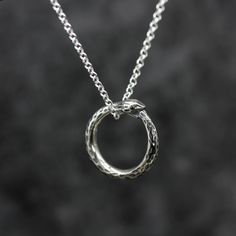 This timeless design reflects the continuous cycle of life and carries a strong symbolic meaning of eternity and self-reflection. Wear it to bring a unique and meaningful accent to your style. Originally handmade, now cast into silver, we finish each and everyone of our ouroboros snake necklaces by hand in our Birmingham Jewellery Quarter workshop. ⸸ Pendant: 20mm x 20mm⸸ Weight: approximately 9.1 g including chain⸸ Chain: 22 inches⸸ 3 - 5 working days Ouroboros Meaning, The Worm Ouroboros, Ouroboros Earrings, Ouroboros Necklace, Spiritual Silver Snake Necklace, Ouroboros Snake, Birmingham Jewellery Quarter, Snake Necklace, Silver Wedding Rings