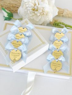 two cards with blue ribbons and gold tags on them next to a bouquet of flowers