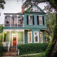 a green house with white balconies and black shutters on the second story