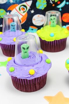 some cupcakes with purple frosting and green sprinkles