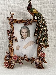 an ornate photo frame with a peacock on the front and side, holding a woman's face