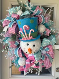 a snowman wreath with a top hat and bow on the front door for christmas