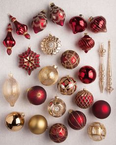 a collection of red and gold ornaments on a white tablecloth, including christmas balls