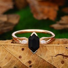 a black diamond ring sitting on top of a leaf