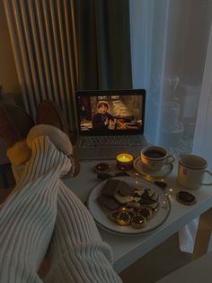 an open laptop computer sitting on top of a table next to a plate of food