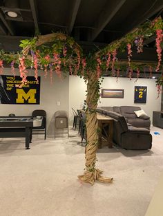 a living room filled with furniture and flowers hanging from the ceiling next to a pool table