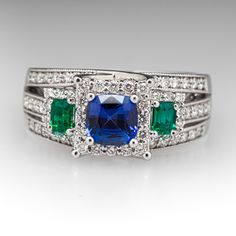 This mesmerizing ring features one (1) prong set cushion cut natural sapphire, two (2) prong set emerald cut natural emeralds, and seventy (70) prong set round brilliant cut diamonds. The ring measures 9.1mm at the top and rises 8.0mm above the finger, tapering to 4.4mm wide and 1.6mm thick at the base of the shank. It is crafted in 18k white gold and is currently a size 7.5. Luxury Multi-stone Emerald Cut Emerald Ring, Emerald Cut Multi-stone Emerald Jewelry, Emerald Cut Multi-stone Gemstones For Wedding, Formal Multi-stone Cushion Cut Jewelry, Elegant Multi-stone Sapphire And Emerald Ring, Emerald-cut Multi-stone Diamond Emerald Ring, Emerald Cut Emerald Ring With Multi-stone Diamond, Cushion Cut Multi-stone Jewelry For Anniversary, Anniversary Cushion Cut Multi-stone Jewelry