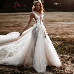 a woman in a wedding dress is standing on the grass with her back to the camera