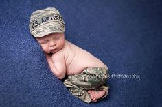 a baby is wearing a us air force hat and sleeping on a blue carpeted area