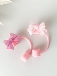 two pink hair clips with bows on them next to a white flower and paper flowers