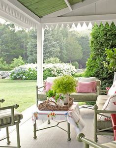 a covered porch with chairs and plants on it