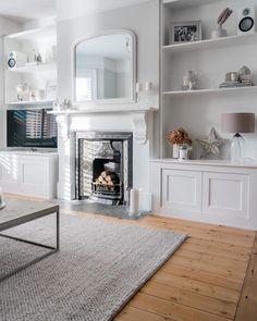 a living room filled with furniture and a fire place in the middle of a wooden floor