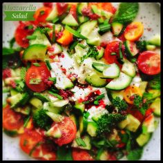 a salad with cucumbers, tomatoes, broccoli and other veggies