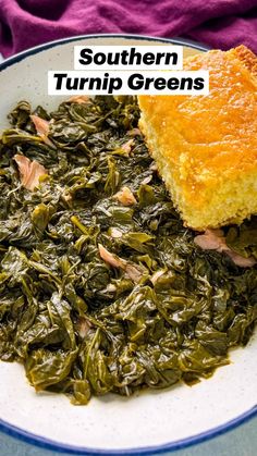 a white plate topped with greens next to a piece of bread