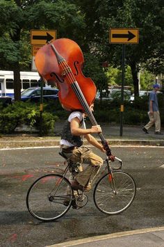 a man riding a bike with a cello on his back