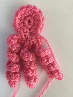 a crocheted pink object sitting on top of a white table next to a pair of scissors