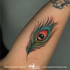 a colorful peacock feather tattoo on the arm