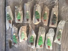 some wooden pieces with green and white christmas tree decorations hanging from it's sides