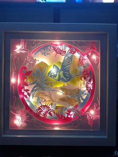 a lit up framed artwork with flowers and birds