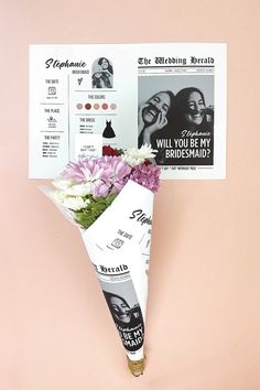 a bouquet of flowers sitting on top of a pink wall next to a paper sheet