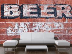 a brick wall with the word beer painted on it and a white couch in front