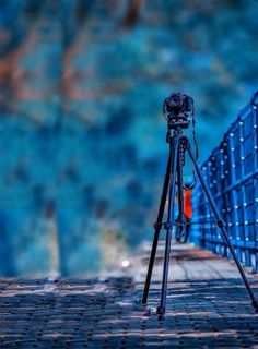 a tripod is sitting on the ground next to a blue wall and some orange balls