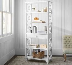 a white bookcase in a living room next to a chair