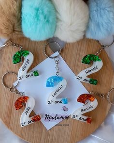 several key chains with different designs on them sitting on a wooden board next to stuffed animals