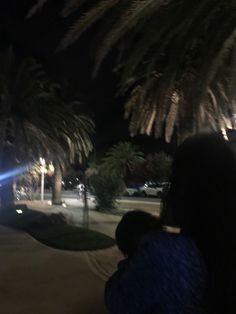 two people sitting under palm trees at night